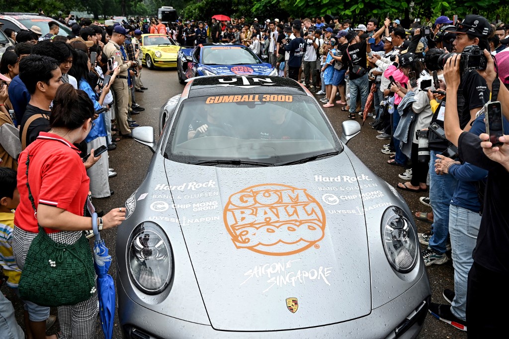 People take photos of supercars taking part in the Gumball 3000 Rally in Cambodia. (AFP Photo)