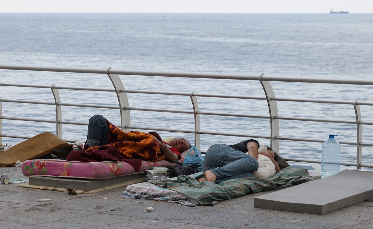 Displaced men sleep on mattresses in the open air on central Beiruts Ain al-Mreisseh seaside promenade